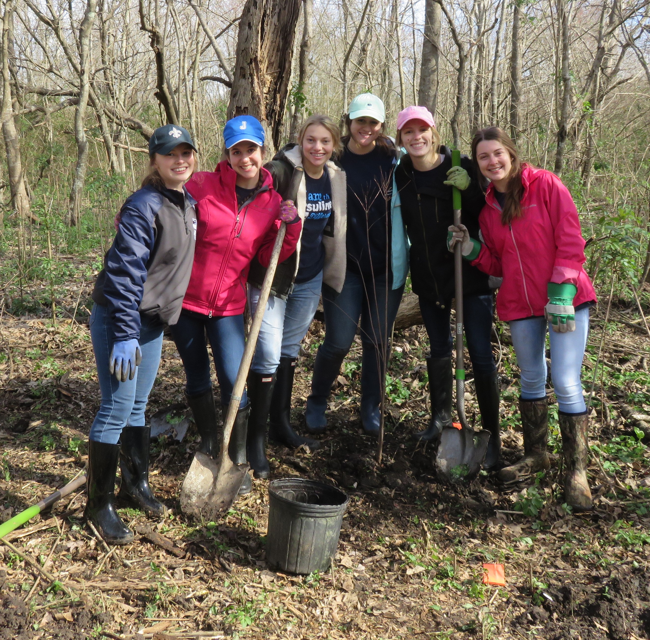 6 smiling Volunteers From Ursuline Academy pose with shoves and empty pots after planting trees. 